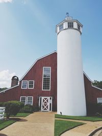 Low angle view of lighthouse by building against sky