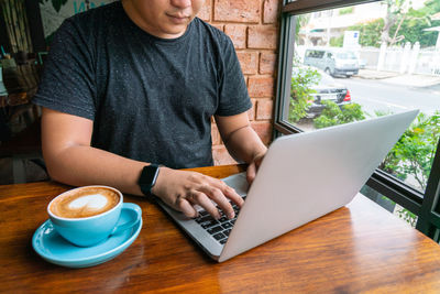 Midsection of man using laptop at cafe