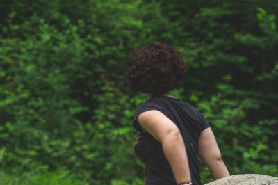 Rear view of woman with short hair standing against tree