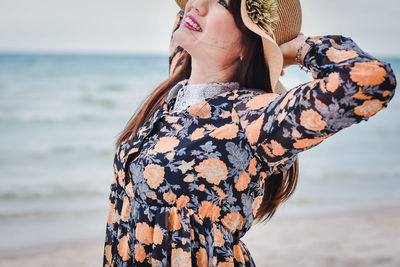 Midsection of woman standing at beach against sky