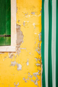 Detail of yellow colored house with window and agh curtain