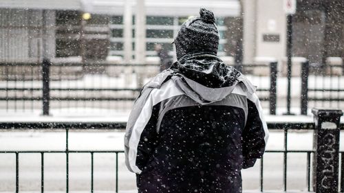 Rear view of a man by railing in snow