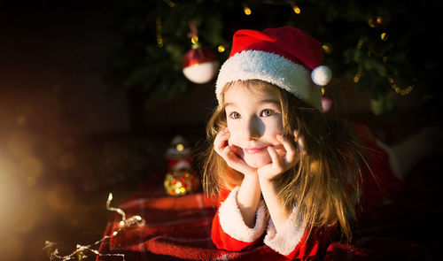 Cute girl lying down by illuminated christmas tree