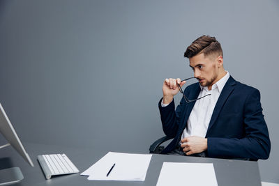 Young man using laptop while standing against white background