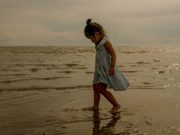 Side view of woman standing on beach against sea