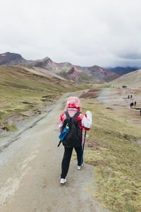 A young woman is hiking to the famous rainbow mountain in peru