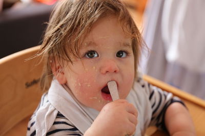 Close-up of cute baby girl with messy face looking away while sitting on chair at home