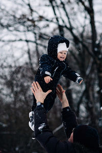 Father tossing daughter mid air during winter