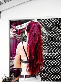 Rear view of woman standing against red wall