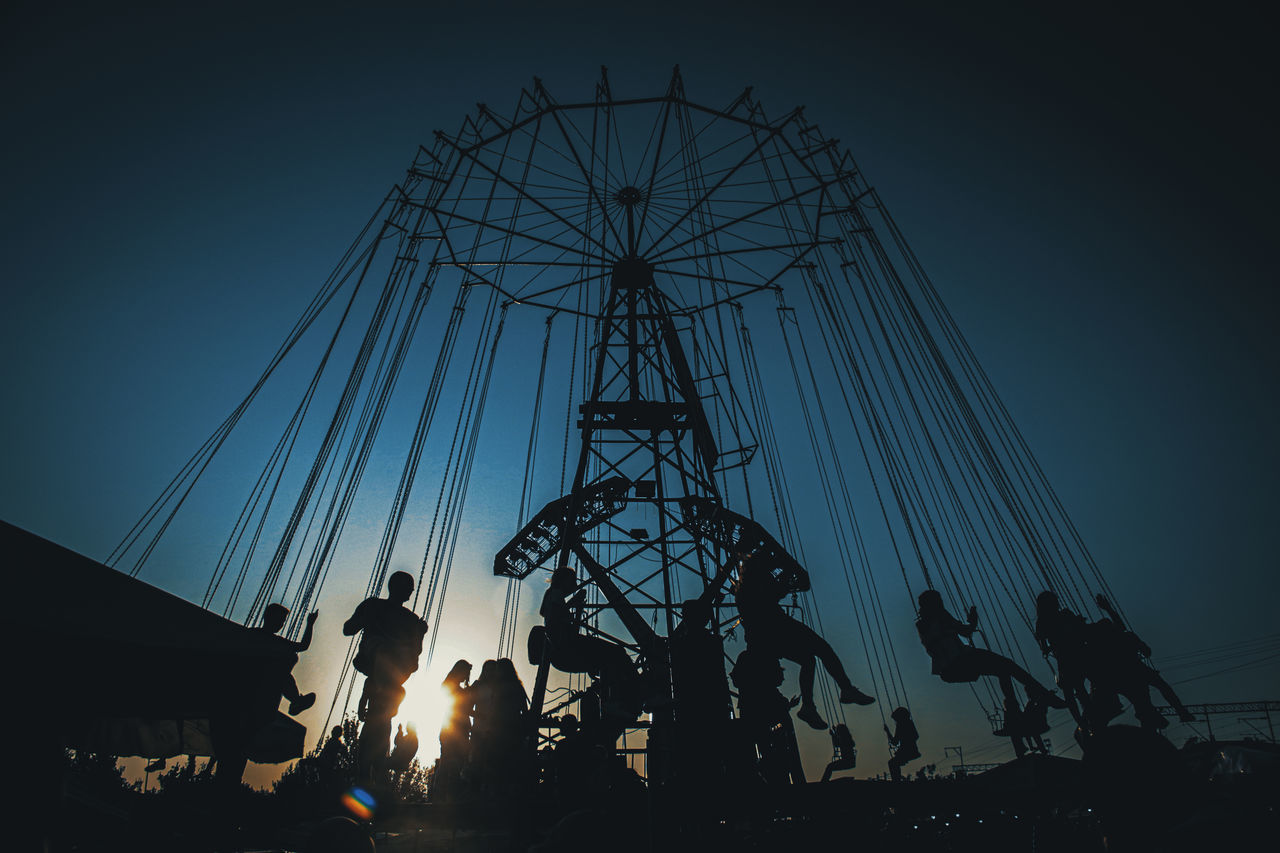 sky, amusement park, arts culture and entertainment, silhouette, amusement park ride, group of people, low angle view, real people, nature, leisure activity, enjoyment, fun, men, blue, outdoors, night, lifestyles, medium group of people, chain swing ride, sunset, fairground