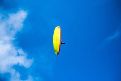 Low angle view of person paragliding against blue sky