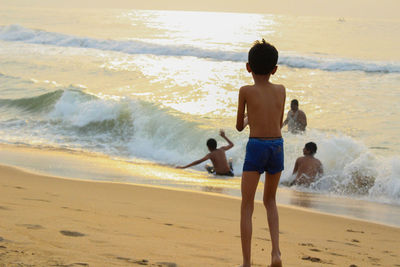 Rear view of shirtless boy on beach