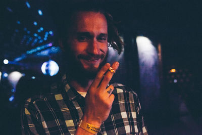 Smiling man smoking while standing in nightclub