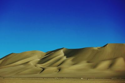 Scenic view of desert against clear blue sky