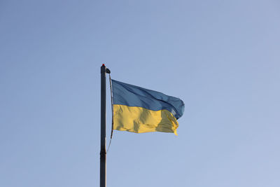 Low angle view of flag against clear blue sky