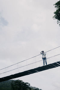 Low angle view of man standing on bridge against sky