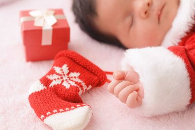 Close-up of baby girl holding christmas stocking while sleeping on bed