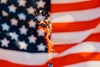 Close-up of lit sparkler against american flag