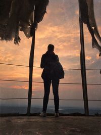 Silhouette of woman standing against sky at sunset