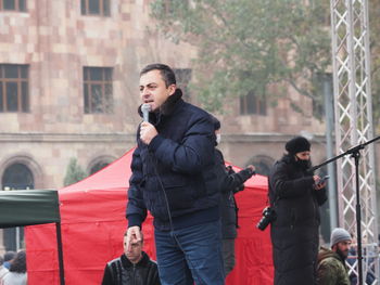 Young man holding camera while standing in city