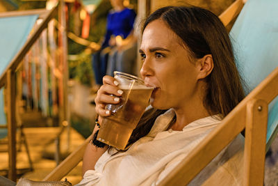 Woman drinking beer while sitting in restaurant