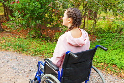 Side view of young woman sitting on wheelchair at park