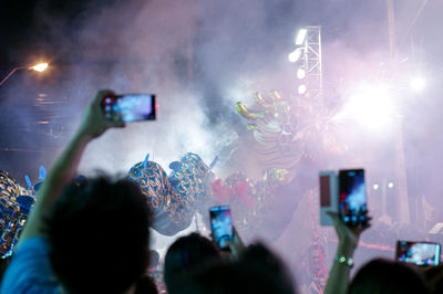 Blurred crowd of people hold the mobile phone recording the blurred dragon dancing with firework