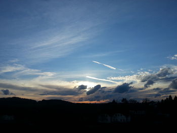 Scenic view of silhouette vapor trail against sky during sunset