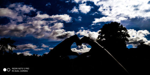 Silhouette woman with arms raised against sky