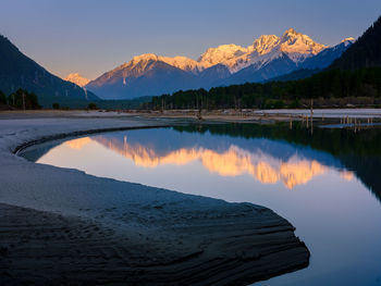 Scenic view of lake by mountains against sky during sunset