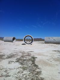 Cement pipes on field against blue sky