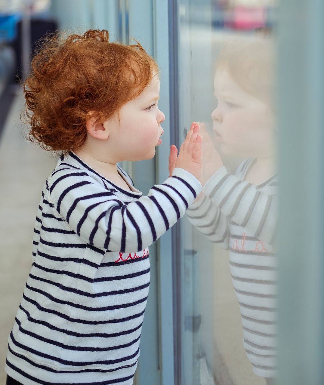 CLOSE-UP OF MOTHER AND DAUGHTER STANDING IN MIRROR