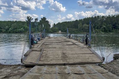 Empty pier over lake against sky