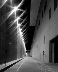 Empty road along illuminated buildings at night