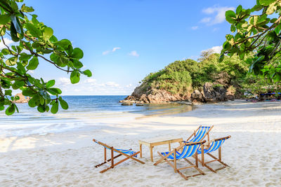 Chairs on beach against sky