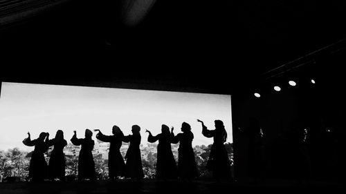 Silhouette people dancing against clear sky