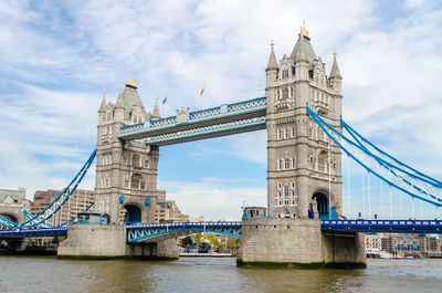 Low angle view of bridge over river against cloudy sky