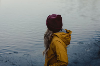 Rear view of woman standing by lake