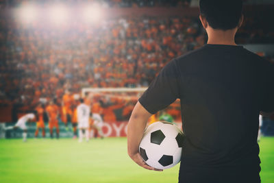 Rear view of referee holding ball while standing on soccer field