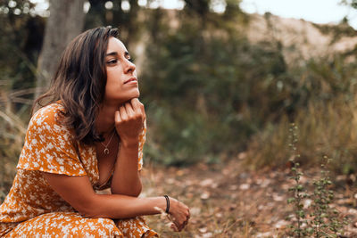 Portrait of beautiful young woman sitting on land