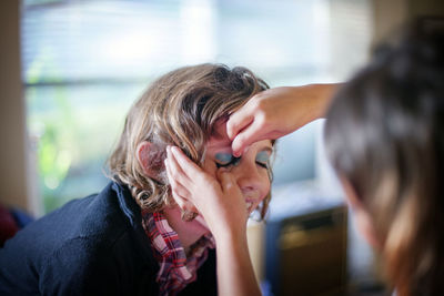 Close-up of sisters applying makeup at home