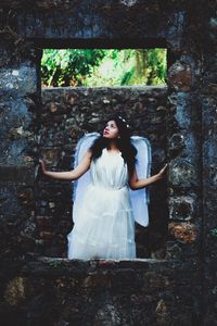 Young woman in fairy costume standing by old ruins