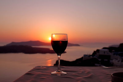 Close-up of wine glass on table during sunset