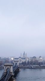 View of buildings by river against sky in city