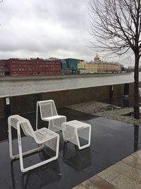 Chairs on beach against sky in city