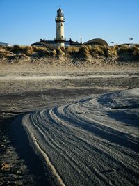 Lighthouse amidst buildings against clear sky