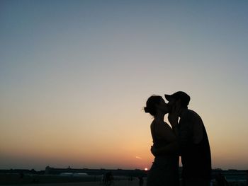 Silhouette couple kissing against sky during sunset