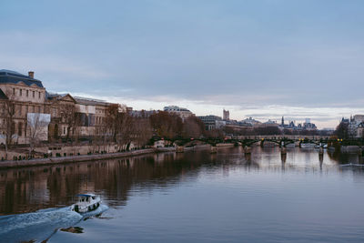 Bridge over river by buildings in city against sky