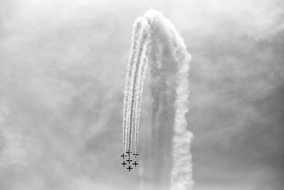 Low angle view of airshow against cloudy sky