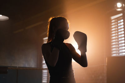 Silhouette woman standing against wall at home